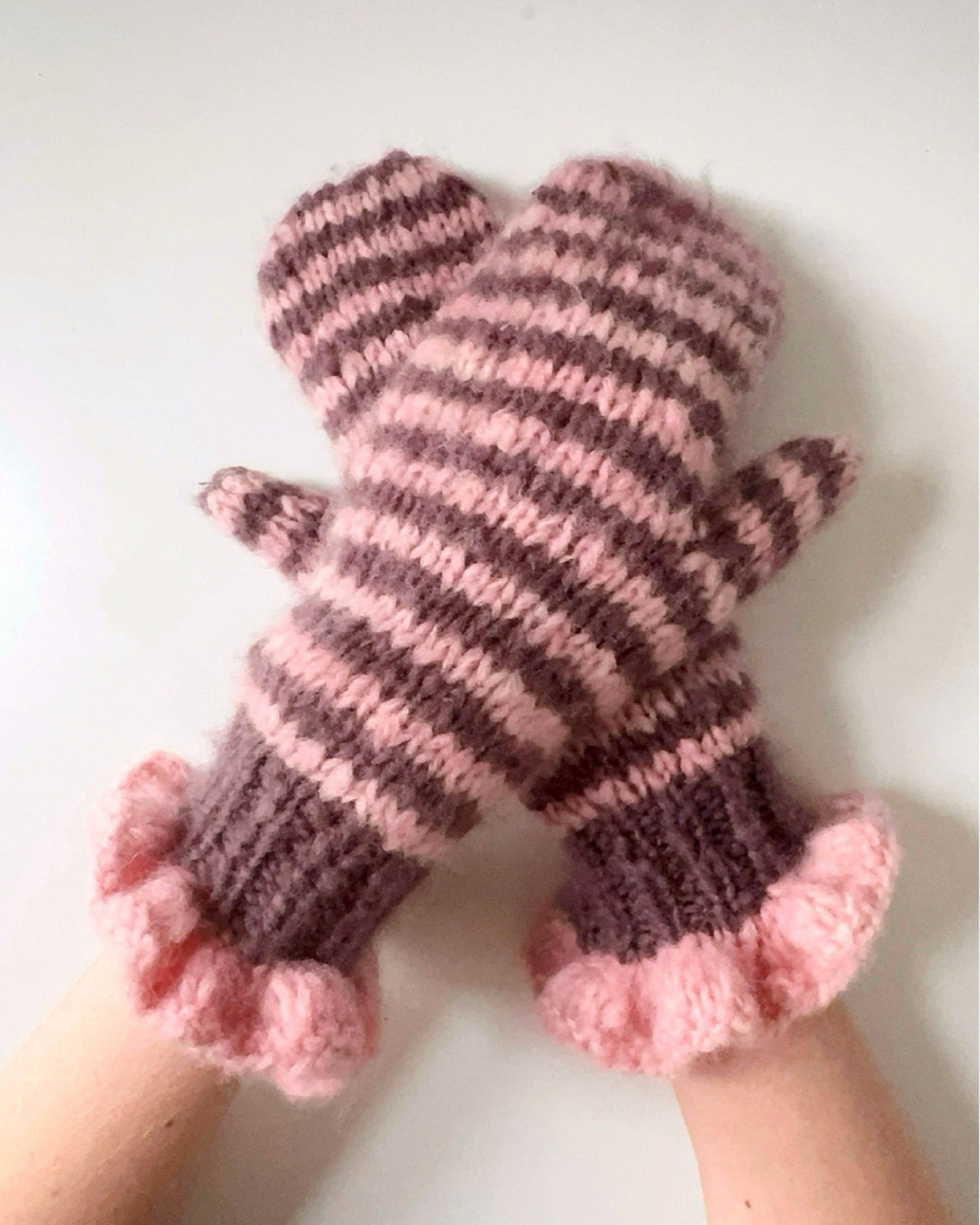 Pair of pink and chocolate striped mittens with frill cuffs on a white background